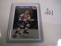 Front view of Bobby Hull hockey card in clear protective sleeve with autograph visible.