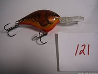 Side and angled views of a brand new Rapala diving fishing lure with crawfish color pattern and two treble hooks.