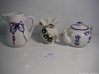 Front view of ceramic pitcher, ruffled edge vase, and flower-decorated teapot