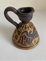 Front side view of mini Greek hydria vase showing black-figure bird motif and ornamental decoration.