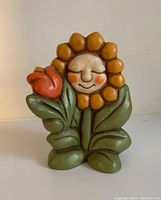 Front view of Thun sunflower ceramic figurine showing puffy petals and smiling face with red tulip detail