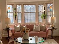 Full view of pink velvet sofa in bay window setting with accent pillows removed
