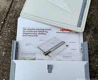 White plastic portable drawing board inside white plastic case with instruction sheet.