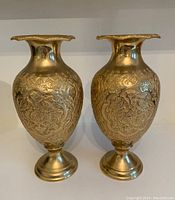 Pair of gold metal urns with etched designs shown upright