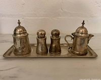 Front view showing all five items on tray: creamer, sugar container, salt and pepper shakers, and tray.