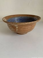 Side view of a brown speckled pottery bowl with a textured surface and flared rim.