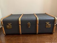 Front view of blue plastic steamer trunk with wood trim and brass locks