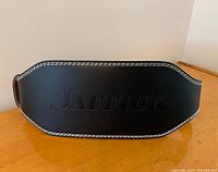 Top view of black leather weight lifting belt with JAFFICK embossed logo and white stitching.