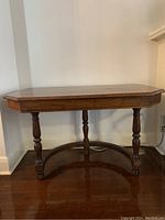 Front view of the solid wood desk showing the rectangular top, curved legs, and circular stretcher base.