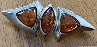 Close-up image of the front of the Baltic amber sterling silver brooch showing three amber stones set in geometric shapes.
