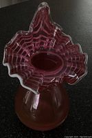 Front and slightly top-down view of the cranberry Fenton Jack in the Pulpit vase showing the ruffled edge and bulbous bottom.
