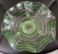 Top view of the green uranium glass bowl showing the wavy ruffled edges and three small hexagonal feet inside the bowl.