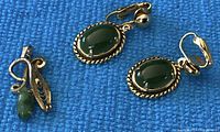 Photo clearly shows two green jade clip-on earrings with gold-tone settings and twisted rope design edges with ball clips, alongside a jade pendant with gold-tone setting and a bail.