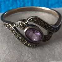 Close-up focus on ring front and amethyst-colored stone with decorative silver band