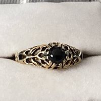 Front close-up of the vintage ladies ring showing black round stone set in detailed gold-tone filigree band.