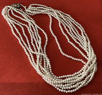 Eight strands of small, white faux pearls laid out to show length and number of strands.