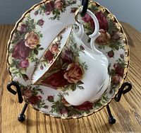 Demi tasse cup resting inside the saucer, showing floral pattern and gold trim on scalloped edges