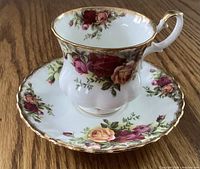Demi tasse cup and saucer set, detailed floral pattern with gold trim, shown from an angle highlighting the cup handle and rim.