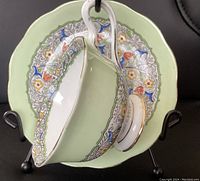 Royal Albert Persian wide mouth teacup resting inside matching saucer, showing floral pattern and gold trim on green background. Handle shows wear.