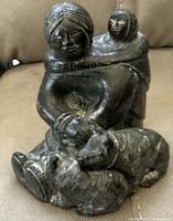 Front view showing mother with baby on back and two wolves lying in front