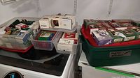 Three large tubs and clear bins containing boxed Hallmark Keepsake ornaments and other Christmas decorations