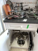 Countertop display: copper-coloured nonstick pan, stacked stainless steel frying pans, soup pots and cooling rack.