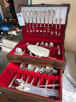 Overall view of flatware laid out in hinged wooden canteen box with red velvet lining showing top and bottom trays.