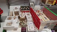 Photo showing assembled Christmas village porcelain ornaments, Santa Claus decorations and boxes with careful packaging.