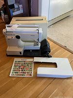 Sewing machine with carrying case, extension table and manual arranged on floor