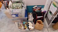 Overall view of plastic bins, tote bag with quilting books, patterns, and other quilting and sewing supplies