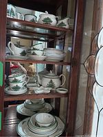Multiple shelves inside wooden hutch displaying Spode Christmas Tree pattern porcelain: teapot, cups, saucers, bowls, platters