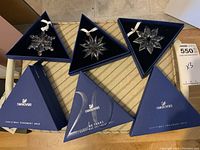 Three triangular boxes open showing 2012 (left), 2011 (center), 2013 (right) ornaments in original packaging