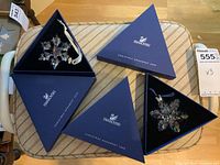 Three Swarovski triangular boxes open with clear crystal snowflake ornaments from 2008, 2009, 2010 displayed