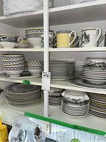 Shelf view showing stacked dinner plates, salad plates, bowls and mugs in Audun Ferme pattern