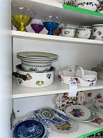 Three-shelf pantry view showing plates, bowls, cups and collector plates