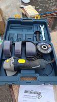 Angle grinder, three grinding discs, handle, wrench arranged inside molded plastic carry case.