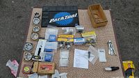 Overview photo showing multiple bike parts including metal taps, small packaged parts, a Park Tool mat, and assorted washers laid flat on textured surface.