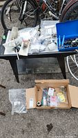 Overview of bike repair tools and parts spread on black table and cardboard box below
