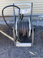 Front view of Suncast hose reel with coiled garden hose and attached spray nozzle.