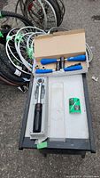 Photo of the Cyclus press in tool with blue handles in a box and the Craftsman torque wrench case on a table with bicycle wheels in the background.