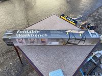 Boxed Ultra Steel Foldable Workbench laid on a table.