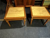 Pair of square side tables with beige marble tops and light wood frames, shown from the top view.