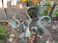 Group of four metal heron sculptures displayed together outdoors
