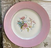 Close-up photo showing a pink border porcelain plate with hand-painted pink wild rose style floral center design.