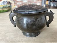 Front view showing entire pot with both handles and engraved art.