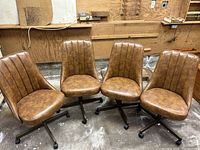 Four brown faux leather swivel chairs arranged together in workshop setting