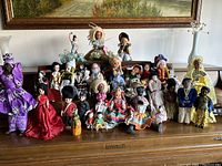 Front view of entire doll collection on wooden surface, showing all 29 dolls in various traditional costumes from different countries and continents.