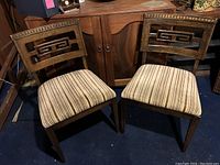 Two matching occasional chairs with striped velvet seats and carved walnut backs, positioned side by side.