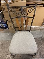 Front view of metal and wood chair showing padded striped seat and decorative backrest detail.