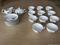 Photo showing the full tea set of 11 cups, 10 saucers stacked, creamer and sugar bowl.